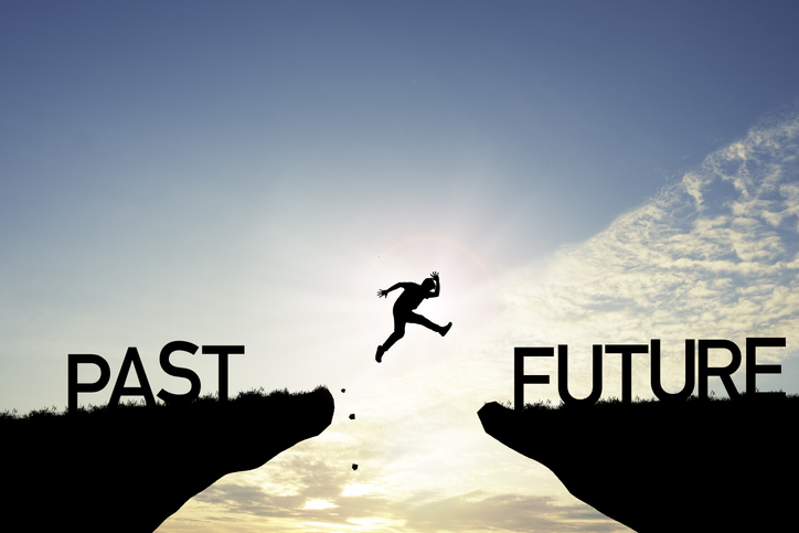 silhouette of person jumping from "past" cliff to "future" cliff