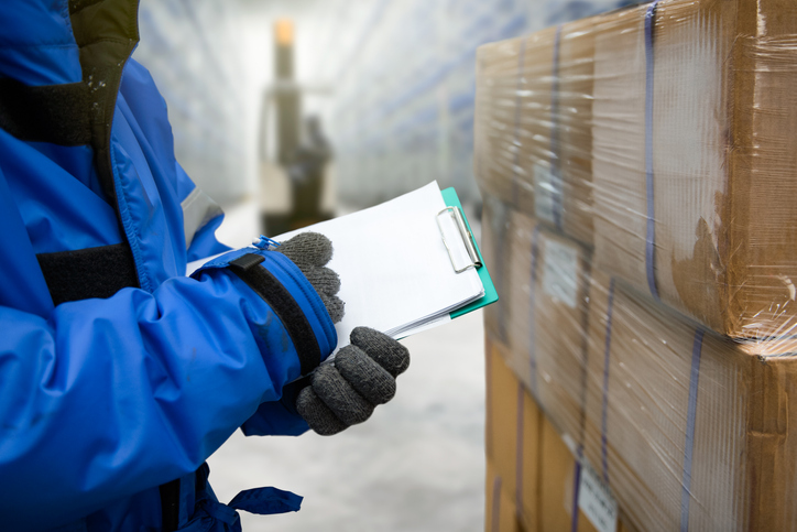 Closeup of employee holding clipboard in refrigerated food processing area