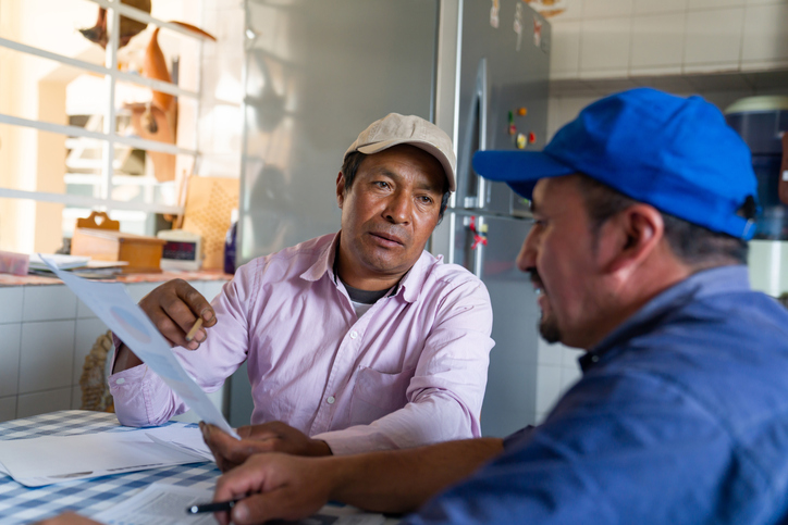 Two Latinx dairy farmers discussing costs and energy efficiency