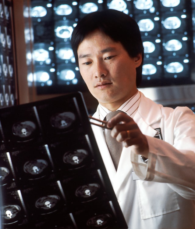 A male Asian radiologist looking at computed tomography (CT) scans.